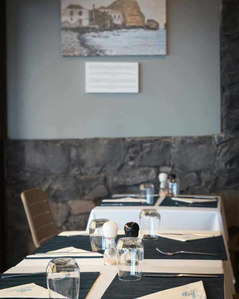 Sala do Restaurante Baía do Bago, com mesas postas e parede de pedra